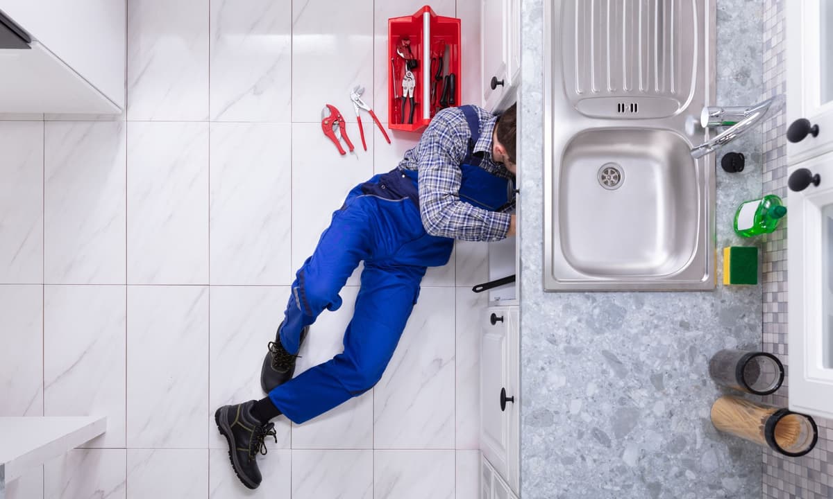 Plumber working under kitchen sink